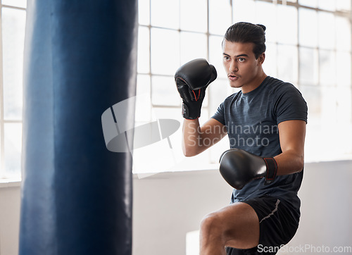 Image of Fitness, boxing and man training for a fight competition, workout or match with a boxing bag in the gym. Sports, motivation and athlete boxer doing MMA exercise to practice in fighting dojo or studio