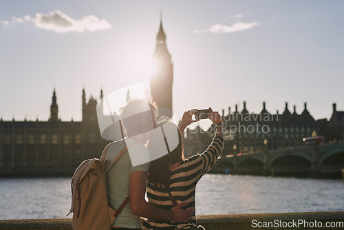 Image of Phone, selfie and couple by the big ben in London on vacation, adventure or holiday together. Travel, building and young tourist man and woman taking a picture on a smartphone in the city in England.