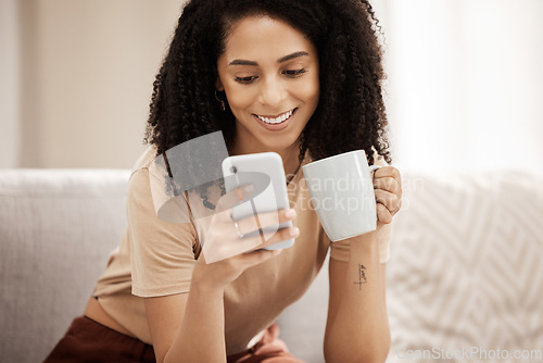 Image of Coffee, phone and woman relax on a sofa, texting, social media and chat in a living room, happy and smile. Tea, black woman and online chatting on a couch, laughing and internet search in her home