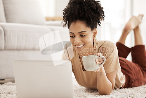 Image of Laptop, coffee and relax with a woman lying on the floor in her home living room over the weekend. Computer, social media and internet with a female typing or reading an email while in her house