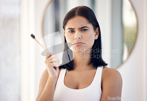 Image of Makeup, beauty and face with a moody woman in the bathroom of her home to apply cosmetics to her skin. Portrait, make up and brush with an attractive young female feeling down or sad in the house