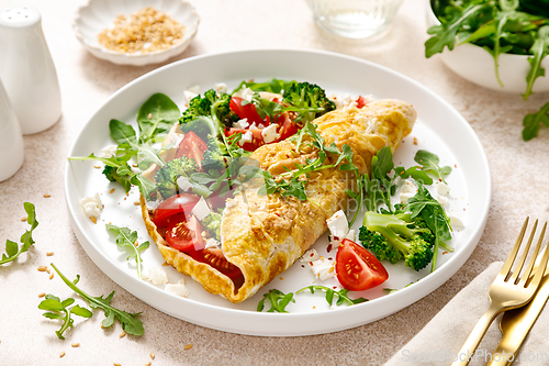 Image of Omelette stuffed with tomato, broccoli feta cheese and fresh green salad. Healthy diet food for breakfast