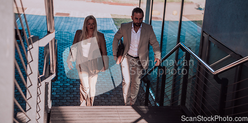 Image of Modern business couple after a long day's work, walking together towards the comfort of their home, embodying the perfect blend of professional success and personal contentment.