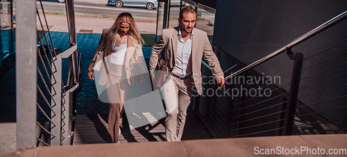 Image of Modern business couple after a long day's work, walking together towards the comfort of their home, embodying the perfect blend of professional success and personal contentment.