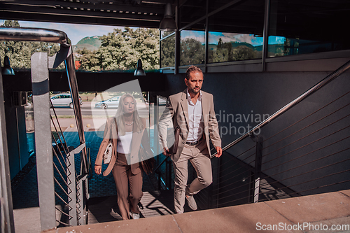 Image of Modern business couple after a long day's work, walking together towards the comfort of their home, embodying the perfect blend of professional success and personal contentment.