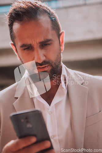 Image of A businessman using his smartphone outdoors, showcasing the seamless integration of technology and mobility in modern professional life.