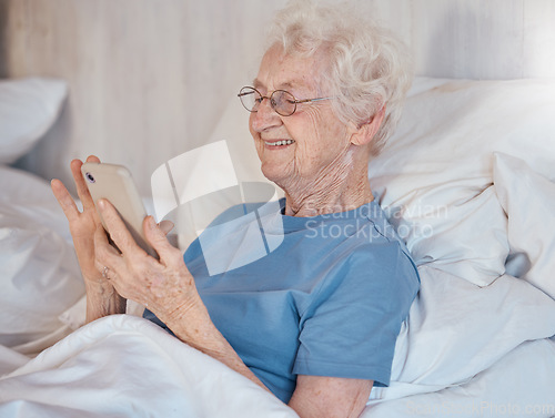 Image of Elderly woman, retirement home and smartphone in bed of nursing home for medical care to relax to support healthcare. Senior with happy smile, in hospital bed and rehabilitation for physical health