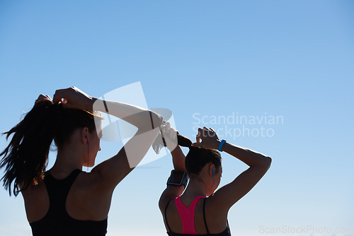 Image of Fitness women, silhouette and blue sky background of runner tying hair together after outdoor run, cardio exercise and wellness health. Healthy running girls, sports athlete and friends morning run
