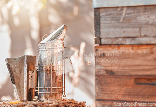 Image of Farm, nature and metal smoker for beekeeping work, protection and harvesting cylinder container. Farming, safety and professional beekeeper tool at wood hive box for harvest and agriculture.