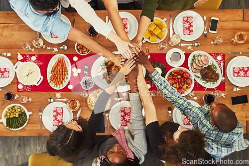 Image of Christmas, high five and food with a group of friends sitting around a dinner table together for celebration. Thanksgiving, hands and meal with a team enjoying a lunch on a wooden surface from above