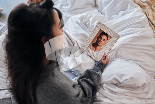 Image of Woman, sad and photo for widow on bed after death, funeral or loss of husband, partner or man. Grief depression, girl and picture memory of love, marriage or anxiety in home bedroom for mental health