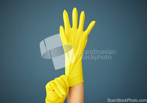 Image of Cleaning, yellow rubber glove and hand on studio background for cleaner, hygiene and spring cleaning mockup on blue background. Hand of woman in uniform for housekeeping and cleaning service mock up