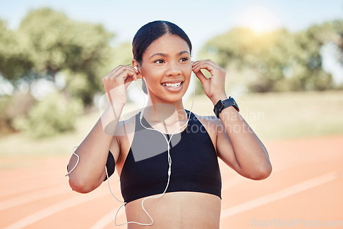 Image of Fitness, exercise and black woman listening to music with earphones for running motivation while outdoor at stadium for marathon or race training. Smile of athlete happy before exercise or run