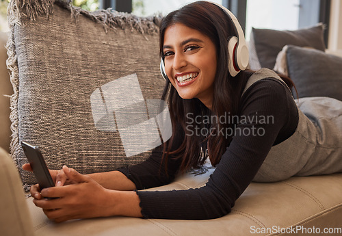 Image of Woman, happy and headphone phone music of a person listening to a podcast or video watching at home. Portrait of an indian person with happiness and smile about mobile technology on living room sofa