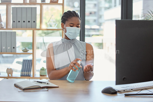 Image of Covid, mask and hand sanitizer with a business black woman cleaning while working in her office. Health, safety and sanitizing with a female employee using disinfectant during the corona virus