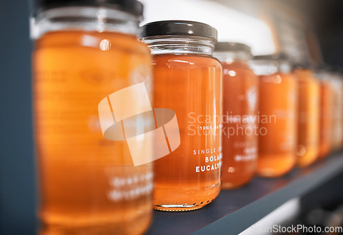 Image of Honey, product and retail with shelf of store for food, supermarket and grocery shopping with nobody. Organic, natural and glass of gold liquid ingredient for vegan, healthy and wellness lifestyle