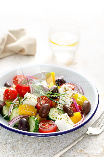 Image of Greek salad. Vegetable salad with feta cheese, tomato, olives, cucumber, red onion and olive oil. Healthy vegetarian mediterranean diet food