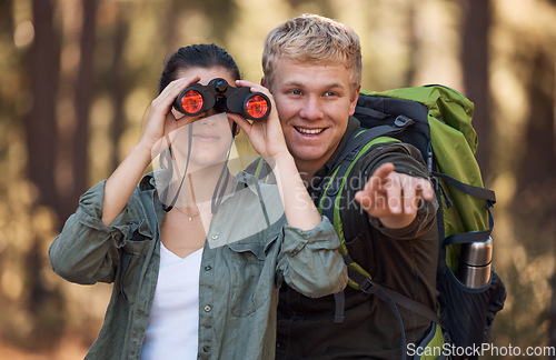 Image of Couple, binoculars and pointing while hiking in nature, travel or outdoors vacation, holiday or trip. Freedom, man and woman on adventure, sightseeing or trekking and looking with field glasses.