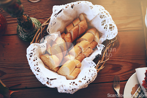Image of Bread, food and basket with a starter serving on a wooden dinner table in a home for a celebration event. Party, lunch and mutrition with a baguette on a surface for eating, dining or a meal
