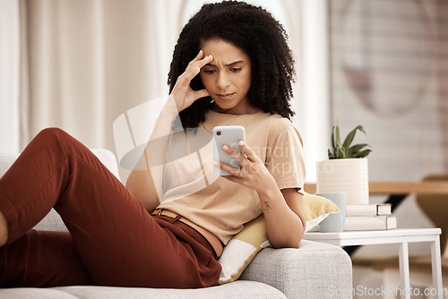 Image of Stress, headache and phone by woman on a sofa with anxiety, bad news or break up text in her home. Confused, black woman and internet glitch on cellphone while texting, social media and browsing