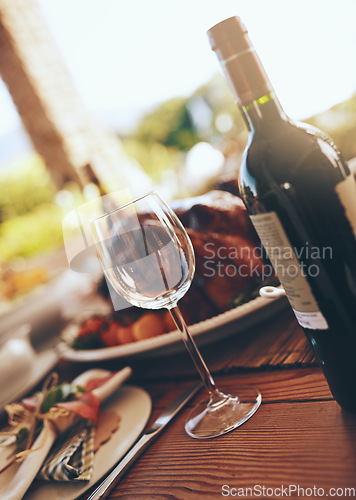 Image of Wine, wine glass and dinner with table at party for Christmas or Thanksgiving celebration with food and drink. Alcohol, celebrate and feast with bottle, drinking and table setting for dinner party.