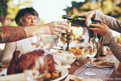 Image of Dinner, party and celebrate with hands and wine, wine glass to pour for drink, people with food outdoor, holiday or anniversary celebration. Festive, event and table with feast, friends and family.