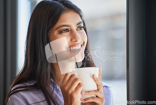 Image of Happy, woman and coffee at a window for relax, thinking and daydream about future, goal and ideas in her home. Face, tea and indian girl smile in her living room, enjoy calm drink and window view