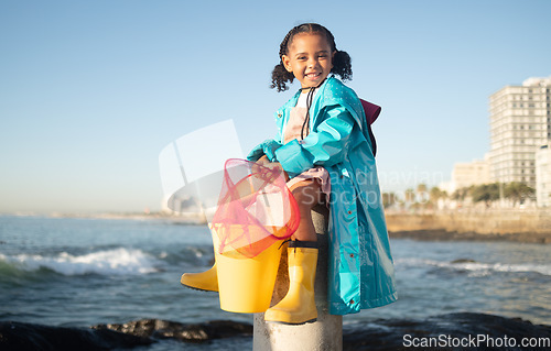 Image of Ocean, fishing and portrait of girl with smile sitting on dock, fun and happy day at beach holiday on the weekend. Nature, blue sky and waves, child at the sea with net ready to catch fish in water