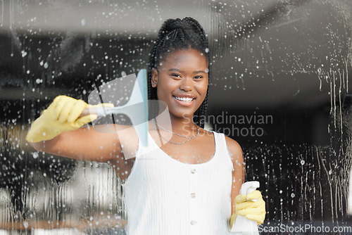 Image of Black woman, portrait smile and washing window for clean hygiene, domestic work or cleanliness at home. Happy African American female spraying soapy detergent on glass windows and wiping surface