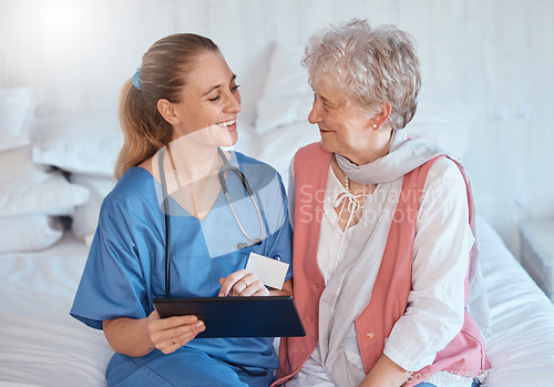 Image of Happy, tablet and nurse consulting an old woman with medical report results or doctor healthcare diagnosis. Smile, bed and social worker helping, talking or speaking to a healthy elderly person