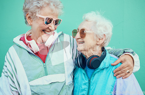 Image of Happy, fashion and elderly friends hug in cool sunglasses, vintage jackets and modern headphones outdoors. Retro, wall background and senior women hugging with pride, freedom and smile in retirement