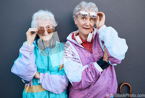 Image of Fashion, funky and friends with a senior woman pair standing outdoor on a gray wall background together. Silly, style and edgy with a trendy mature female and friend having fun while bonding