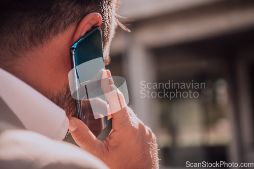 Image of A businessman using his smartphone outdoors, showcasing the seamless integration of technology and mobility in modern professional life.