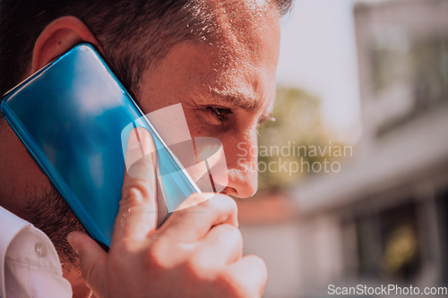 Image of A businessman using his smartphone outdoors, showcasing the seamless integration of technology and mobility in modern professional life.