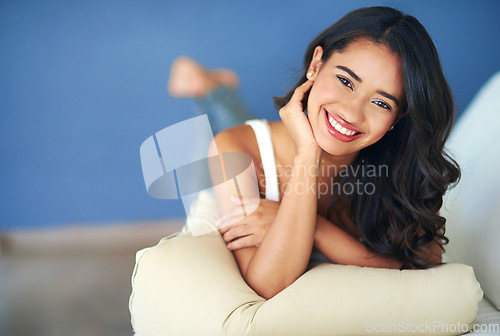 Image of Face, portrait and woman lying on sofa in living room of home alone. Happy, smile and young female from India relaxing on her comfortable couch in lounge, smiling and enjoying quality time in house.