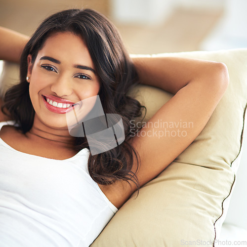 Image of Relax, smile and portrait of woman on sofa for happy, luxury and lifestyle. Comfortable, happy and content with girl lying on couch in living room at home for lounge, break and rest on weekend