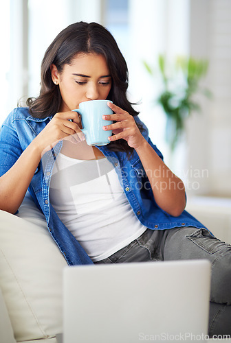 Image of Woman, laptop and relax on sofa with coffee for morning routine, working online or read social media communications on tech. Drink tea, peace on couch and streaming news or web blog on computer