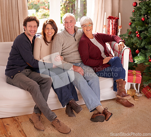 Image of Family, christmas and love for holiday celebration with a happy couple and their senior parents together on a living room sofa. Men and women on couch to celebrate christian tradition at home