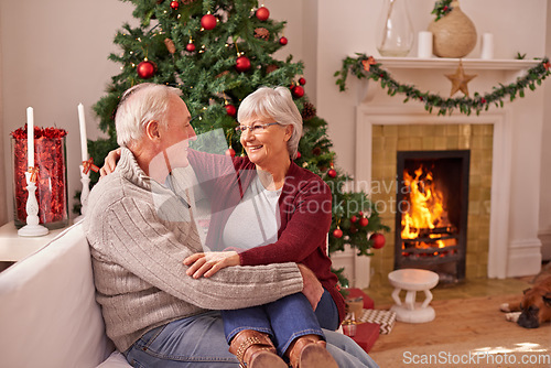 Image of Christmas, love and senior couple on sofa in home bonding and affection. Xmas, romance and elderly, retired woman sitting on lap of man and cuddle on couch by fireplace enjoying holiday time together