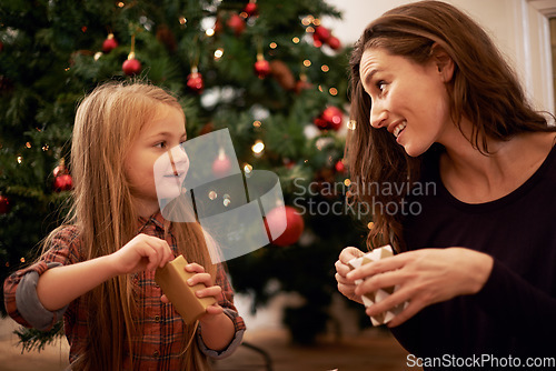 Image of Christmas gifts, family and mother with girl, having fun or bonding in home. Love, care and happy mom with child opening presents on xmas day, smile or enjoying quality holiday time together in house