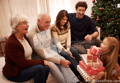 Image of Christmas, happy family and child with a gift for excited grandparents at home on a winter holiday celebration. Wow, mother and father with a young girl kid giving present boxes to old man and woman