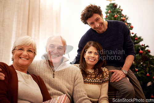 Image of Christmas, family and visit with a man, woman and senior parents together in the living room of a home. Portrait, happy and bonding with a mother, father and in laws celebrating the festive season