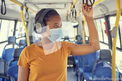 Image of Travel, face mask and woman on a bus with headphones to listen to music, radio or podcast on the trip. Journey, transport and African girl standing in vehicle with a mask for covid regulations safety