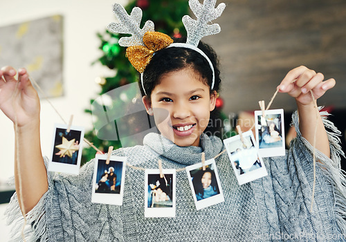 Image of Christmas, celebration and girl with polaroid for decoration, happy and show photos in the house. Smile, excited and portrait of a child with pictures to decorate the home for a festive xmas
