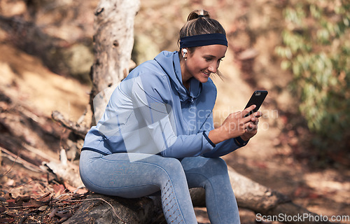 Image of Fitness, woman with smartphone and earphones for music search, run in the woods with technology and audio streaming for workout. Wellness, happy and runner with radio app and exercise outdoor.