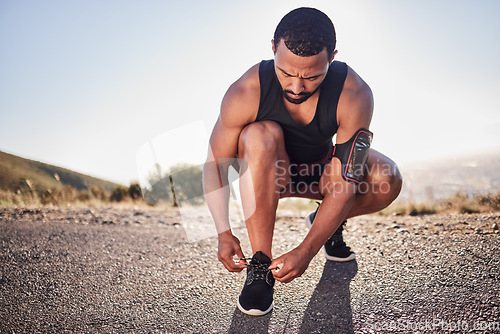 Image of Fitness, tie and shoes of a man on a road for running, cardio workout or training for a marathon in summer. Focus, wellness and healthy sports athlete runner tying footwear laces to start exercise