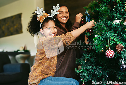 Image of Christmas tree decoration, family and girl with mother helping in home living room. Portrait, festive season and happy child with mom decorating with ornaments and preparing for xmas party in house.