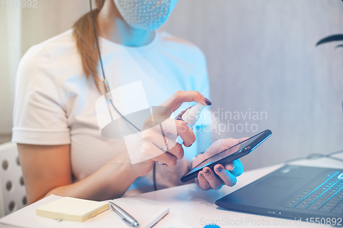 Image of Woman disinfects the surface of the phone