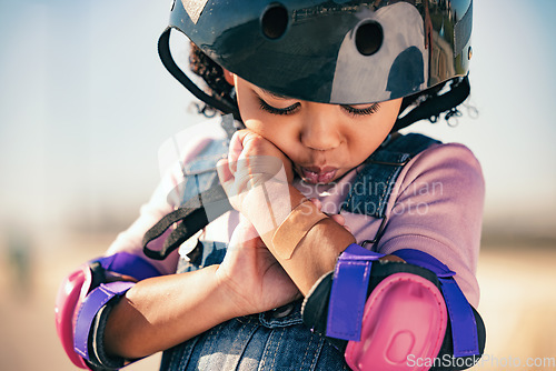 Image of Children, skater and plaster with an injured girl looking at her sore arm while skating outdoor in a helmet and pads. Training, safety and injury with a female kid in pain after a sports accident