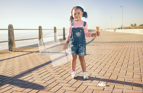 Image of Upset little girl, ice cream and sad in Cape Town with expression in frustration for a spoilt day by the ocean bay. Unhappy moody child holding empty icecream cone melting mess on floor at sea point